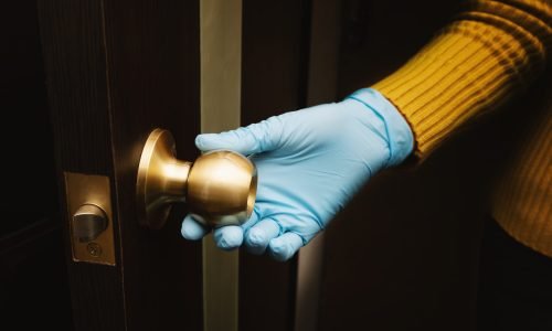 Female hand in protective glove open a door.