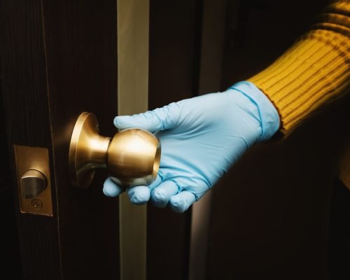 Female hand in protective glove open a door.