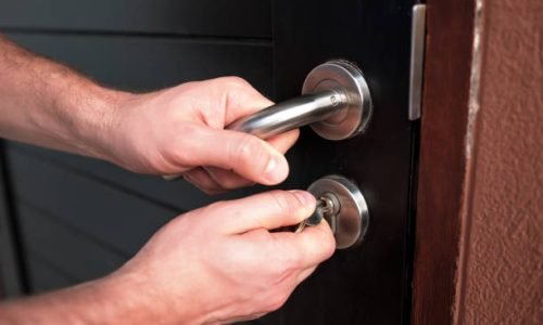 Man hand opening black door with key close up